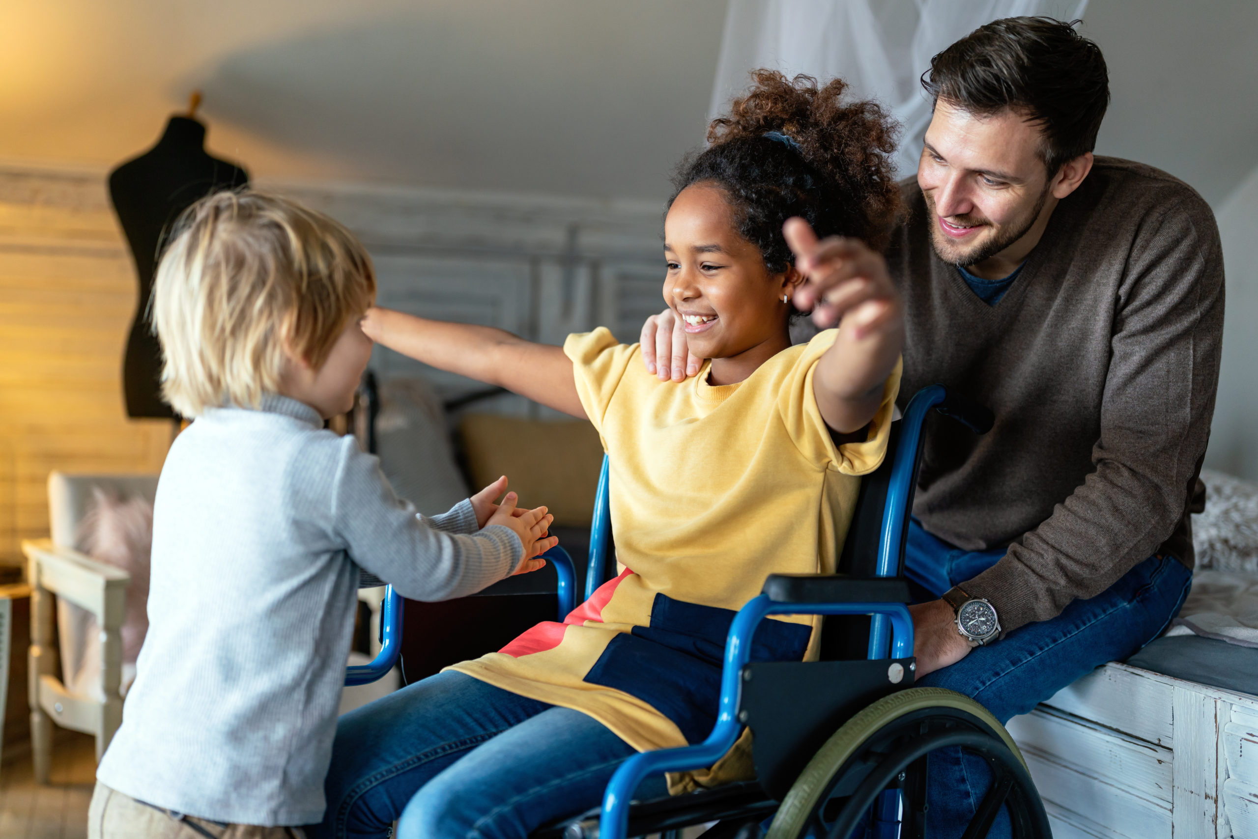 little girl on wheelchair playing with dad and sibling